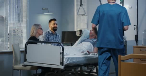 Paciente do sexo masculino deitado no hospital entre a família — Vídeo de Stock