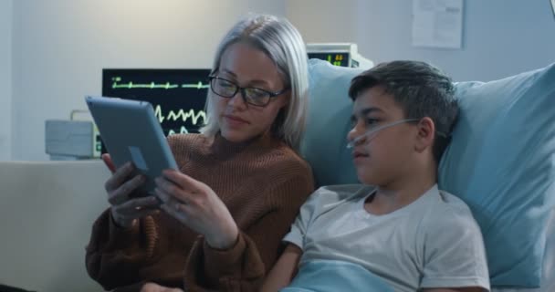 Mutter benutzt Tablette mit krankem Sohn — Stockvideo