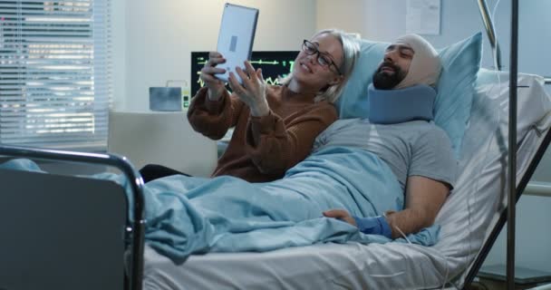 Mulher mostrando usando tablet com o homem ferido — Vídeo de Stock