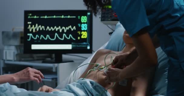 医師は心拍数をチェックするために患者にケーブルを置く — ストック動画