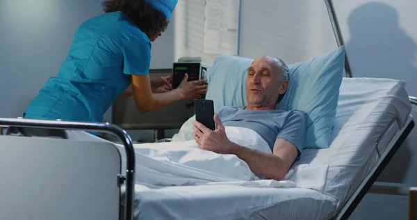 Paziente di sesso maschile che utilizza la videochiamata in camera d'ospedale — Foto Stock