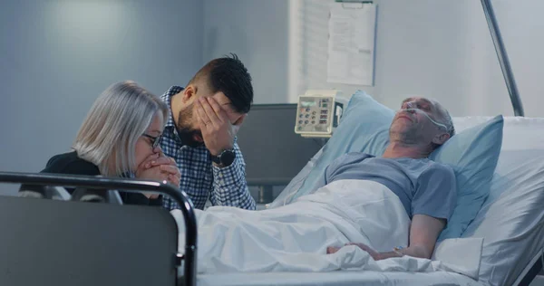 Man lying in hospital among family — Stock Photo, Image