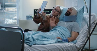 Yaralı adamla tablet kullanan bir kadın görülüyor.