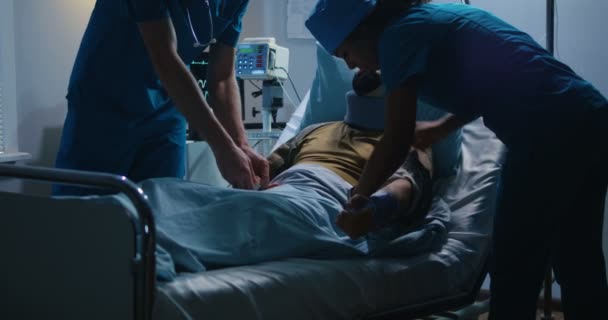 Раненый солдат лежит в больнице среди врачей — стоковое видео
