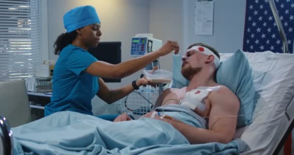 Sjuksköterska utfodring skadad soldat i sjukhussäng — Stockvideo