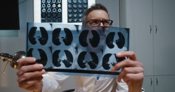 Doctor explaining diagnosis to camera with MRI scan — Stock Video