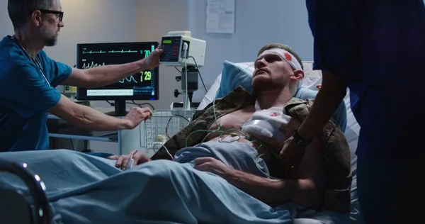 Раненый солдат лежит в больнице среди врача и медсестры — стоковое фото