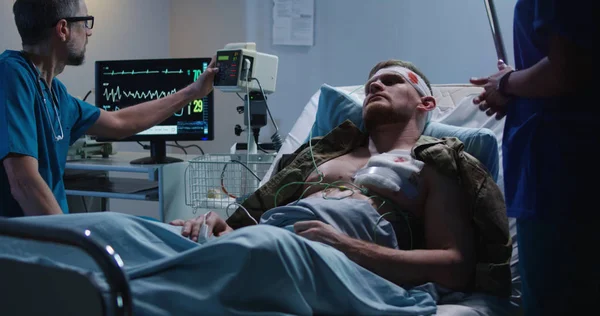Раненый солдат лежит в больнице среди врача и медсестры — стоковое фото