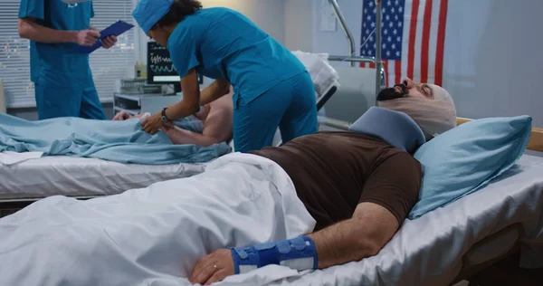 Doctor and nurse visiting injured soldiers in hospital — Stock Photo, Image