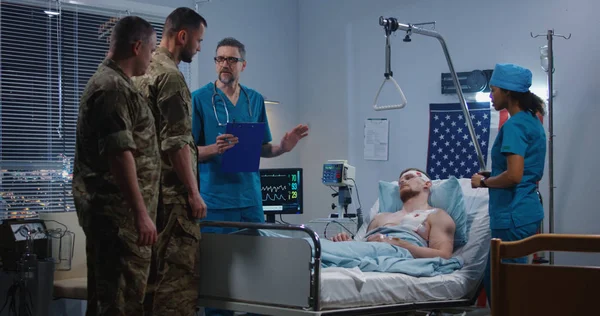 Medico che mostra raggi X ai soldati visitatori in ospedale — Foto Stock