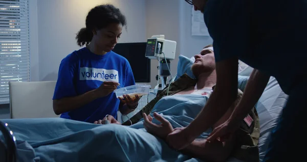 Krankenschwester füttert verletzten Soldaten im Krankenhausbett — Stockfoto