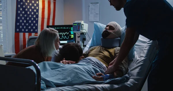 Поранений солдат лежить у ліжку серед сім'ї та медсестри — стокове фото