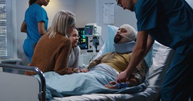 Aile ve hemşire arasında yatakta yatan yaralı asker