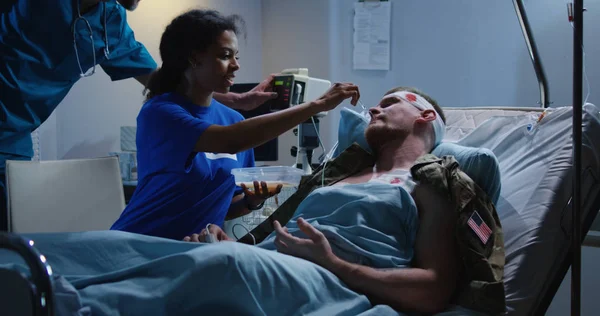 Медсестра кормит раненых солдат на больничной койке — стоковое фото