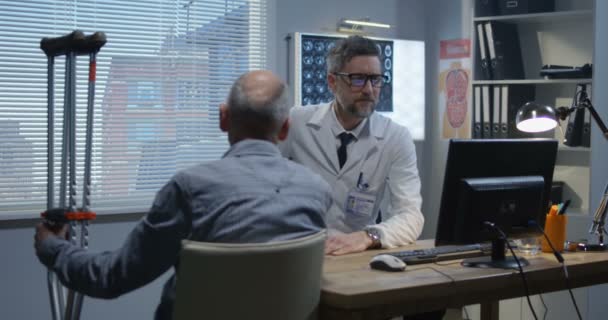 Врач-мужчина объясняет диагноз пациенту-мужчине — стоковое видео