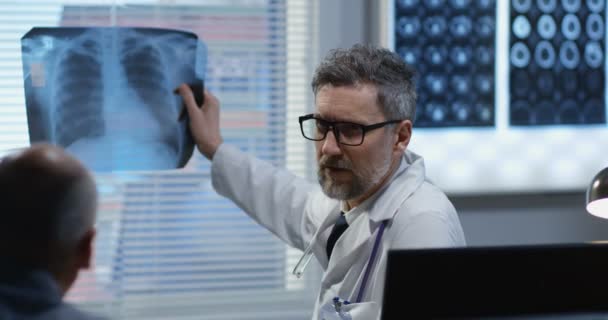 Male doctor showing x ray to patient — Stock Video