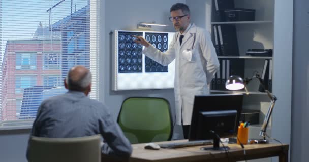 Врач-мужчина, объясняющий пациенту сканирование мозга — стоковое видео