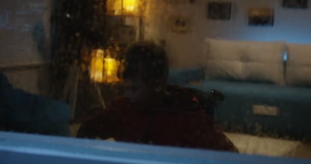 Wheelchaired boy watching storm from room — Stok Video