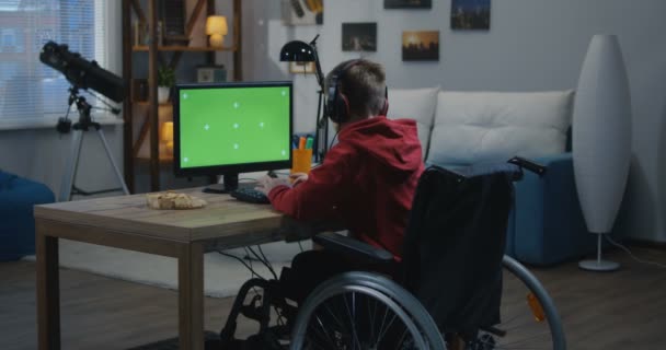 Chico con silla de ruedas usando computadora — Vídeo de stock