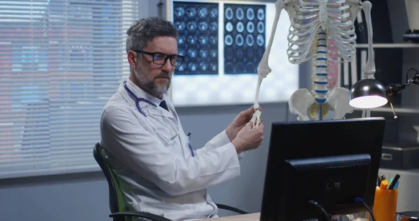 Mężczyzna lekarz analizujący ludzki szkielet model — Zdjęcie stockowe