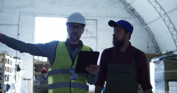 Dos hombres discutiendo en un almacén — Vídeo de stock