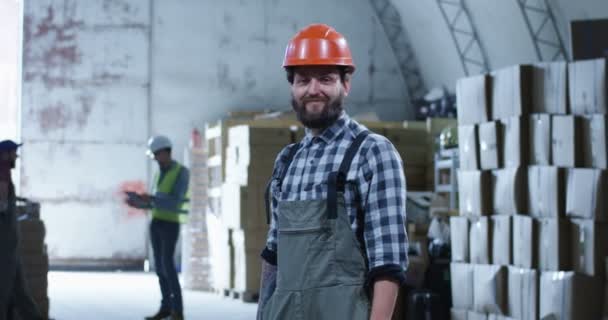 Arbeiter lächelt in einer Lagerhalle in die Kamera — Stockvideo