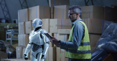 Depoda çalışan robotu izleyen adam