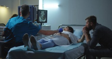 Gelecek çocuğun ultrason görüntüsünü izleyen çift