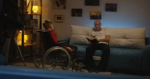 Opa lezing naar gehandicapte jongen — Stockfoto