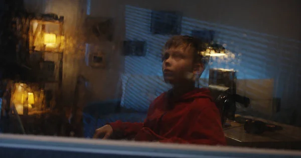Мальчик с инвалидным креслом наблюдает шторм из комнаты — стоковое фото