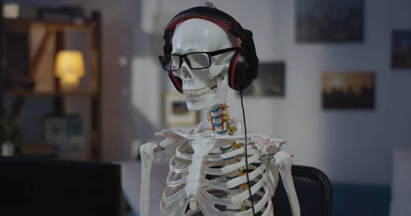 Σκελετός με ακουστικά που κάθονται στον υπολογιστή — Φωτογραφία Αρχείου