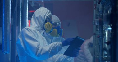 Hazmat kıyafeti giyen bilim adamları bakım yapıyor