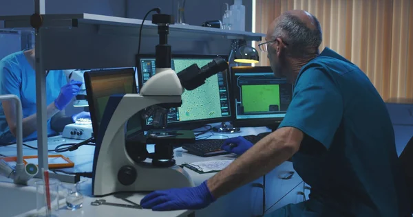 Biolog analyzuje vzorek mikroskopem — Stock fotografie