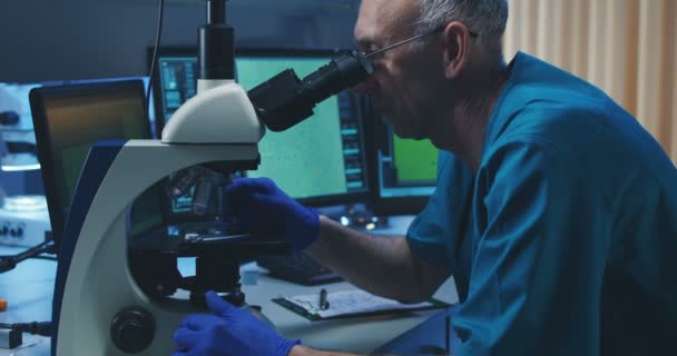 Biólogo analizando muestra con microscopio — Vídeo de stock