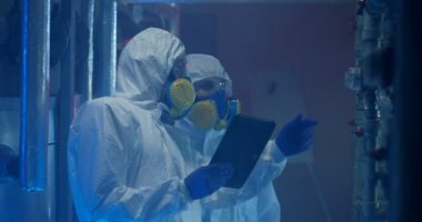 Hazmat kıyafeti giyen bilim adamları bakım yapıyor