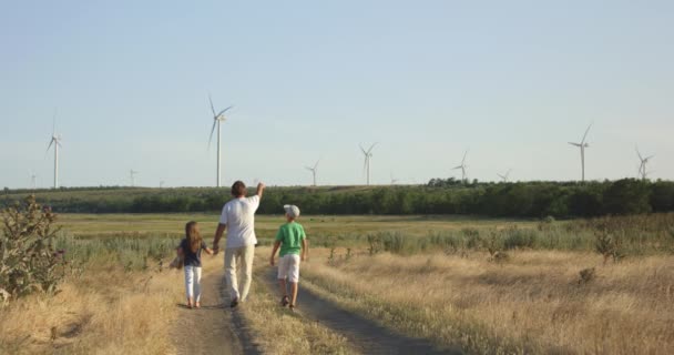 Père montrant des moulins à vent aux enfants 