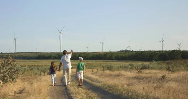 Pai mostrando moinhos de vento para crianças — Fotografia de Stock