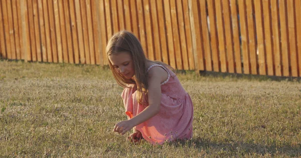 Little girl crouching in field — Stock Photo, Image