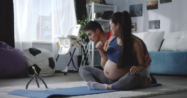 Mężczyzna i kobieta w ciąży oglądając film podczas treningu — Wideo stockowe