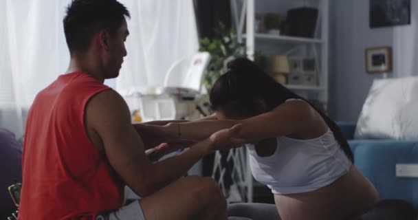 Молодий чоловік навчає вагітної жінки під час тренування — стокове відео