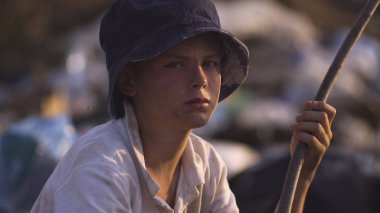 Kirli yüzlü çocuk kameraya bakıyor