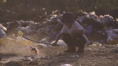 Çöplükte çömelmiş çocuk