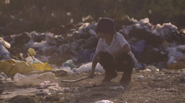 Çöplükte çömelmiş çocuk