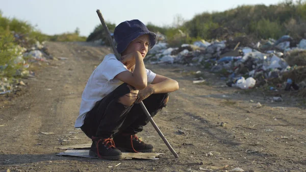 Dirty faced boy crouching at landfill — Stock Photo, Image