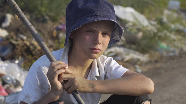 Dirty faced boy crouching at landfill — Stock Photo, Image