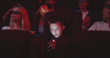 Sinemada akıllı telefon kullanan çocuk