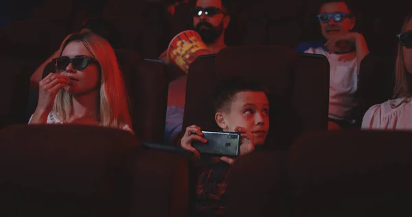 Boy pirating movie in cinema with smartphone — Stock Photo, Image