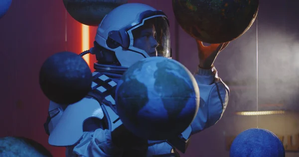 Student in space suit revolving planet model