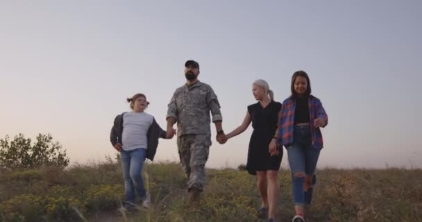 Żołnierz i jego rodzina chodzą na łące — Wideo stockowe