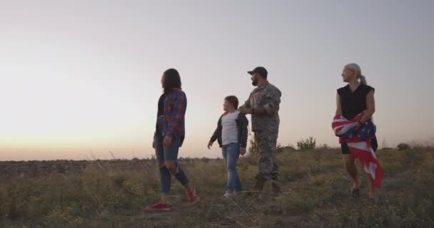 Soldat und seine Familie gehen auf einer Wiese spazieren — Stockvideo